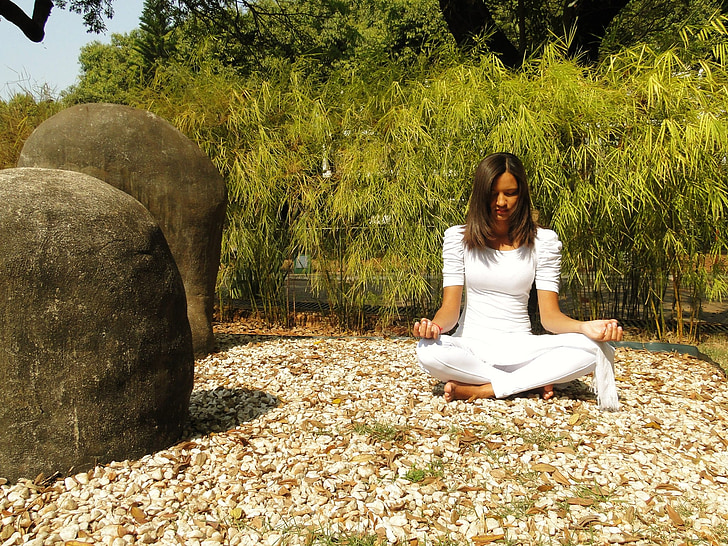 woman meditating surrounded with green trees