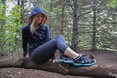 woman wearing hoodie sitting on tree log
