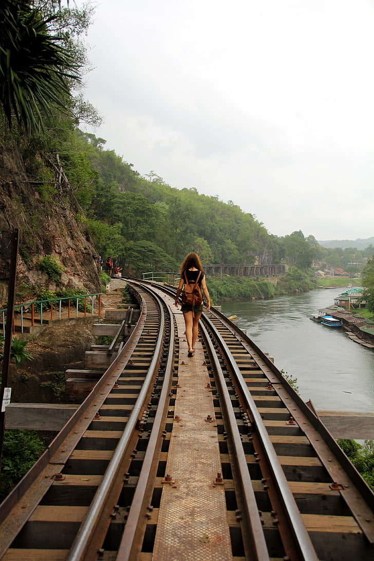 woman waling on brown metal rail road during daytime