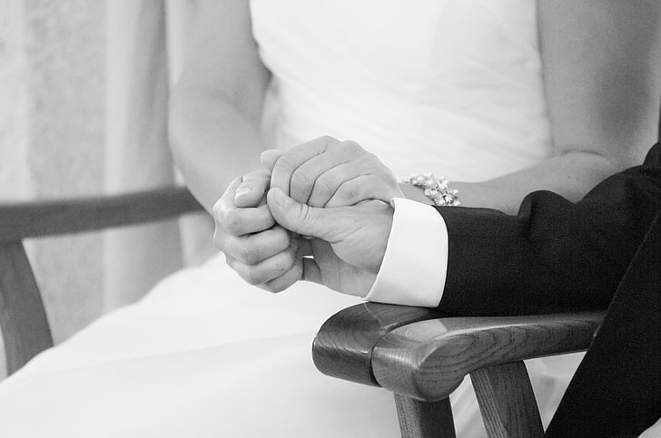 grayscale photography of groom and bride holding their hands together