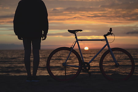 man standing beside bicycle near seashore