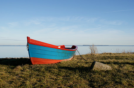 wooden boat on field of grass fronting sea