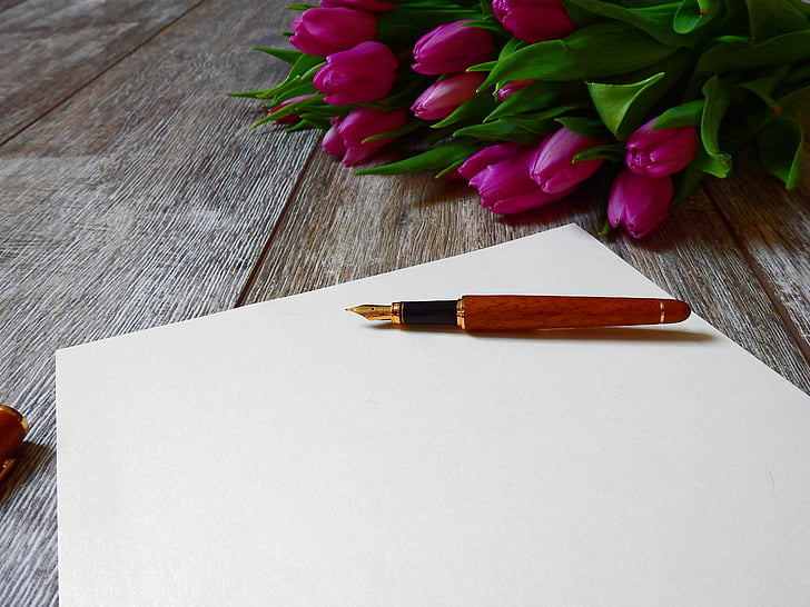 red fountain pen near bouquet of pink tulips