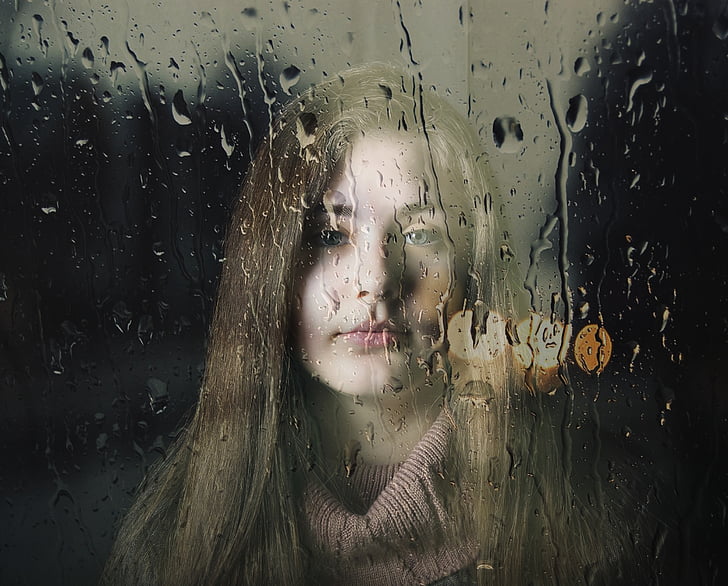 closeup photography of woman behind wet glass