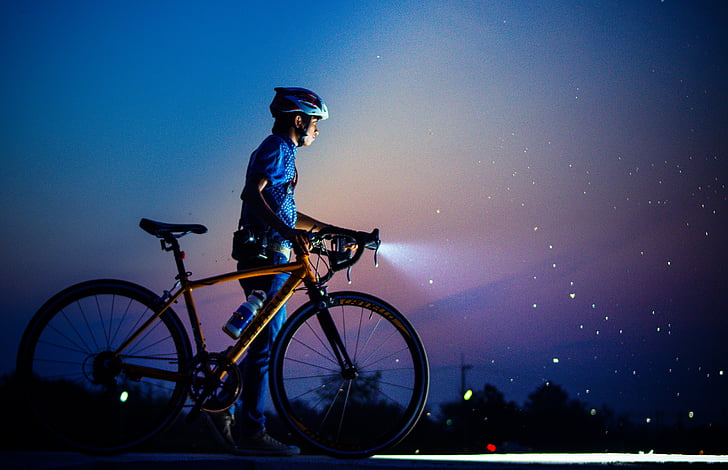 photo of man wearing blue top holding brown rigid road bike