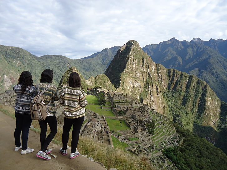 three women standing while looking at mountain range