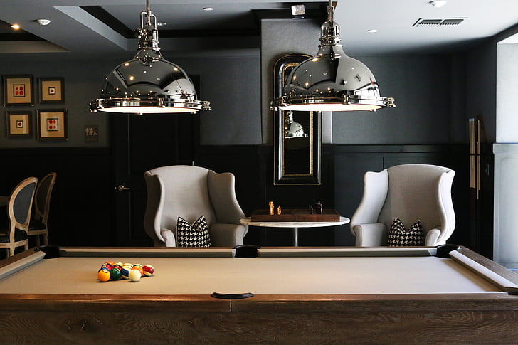 two silver-colored pool lamp and brown pool table