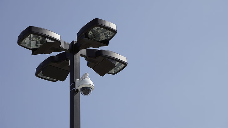 white surveillance camera mounted on black post