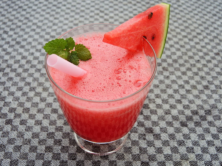 watermelon shake on clear drinking glass with slice of watermelon and white straw