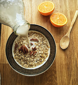 oatmeal with wallnuts inside bowl on beside sliced orange fruits photography