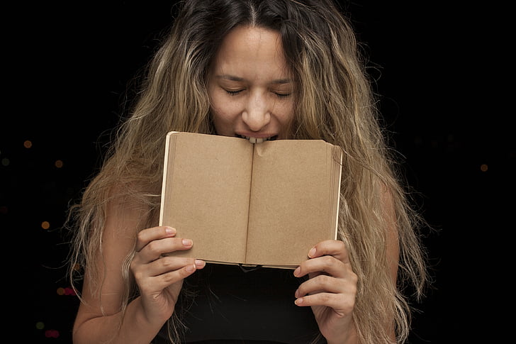woman biting a brown book