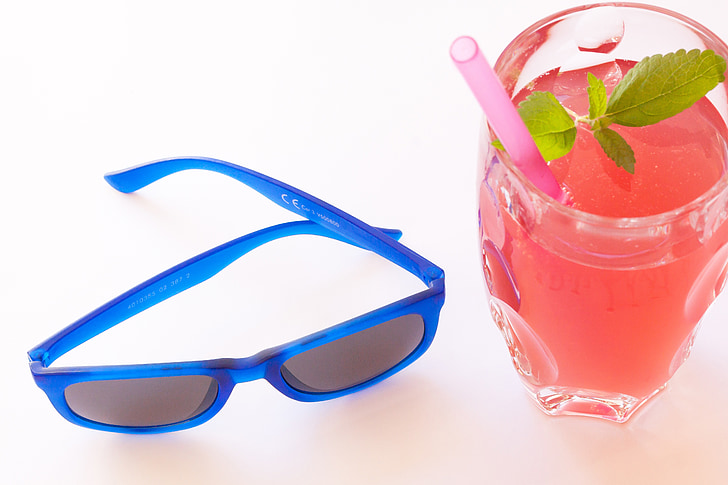 blue framed Wayfarer-style sunglasses near glass cup with juice drink