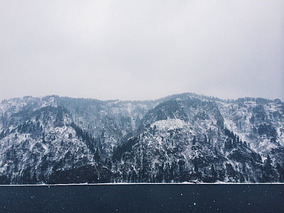 mountain covered by snow beside body of water