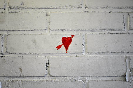white brick wall with red heart painting