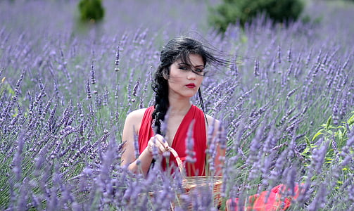 woman wearing red sleeveless top surrounded by purple petaled flowers