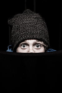 person wearing knit hat peeking on black textile