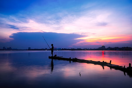 Silhouette man fishing in lake