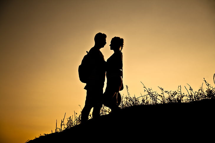 silhouette of man and woman on hill at golden hour