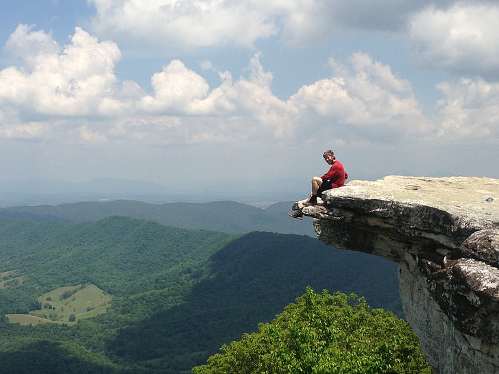 man sitting on ledge of rock