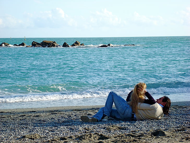 couple laying on beach side photography