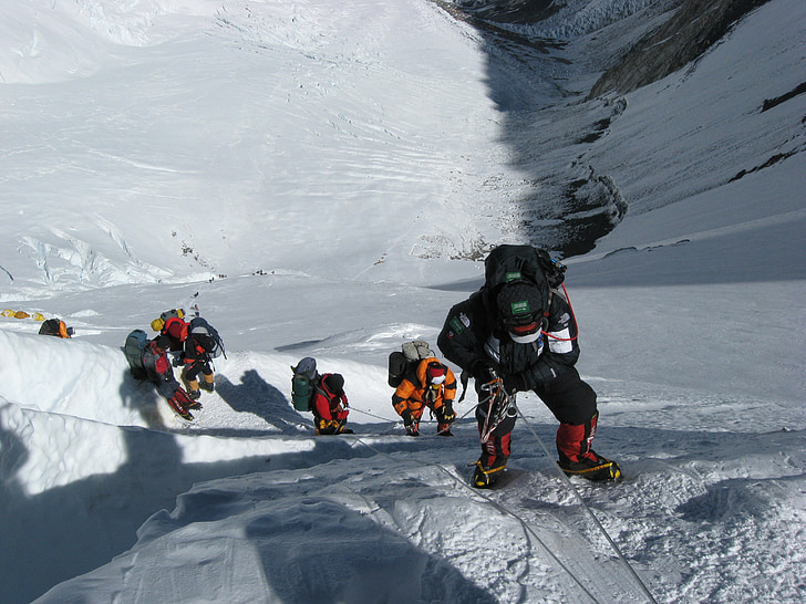 group of people hiking on snow mountain cliff