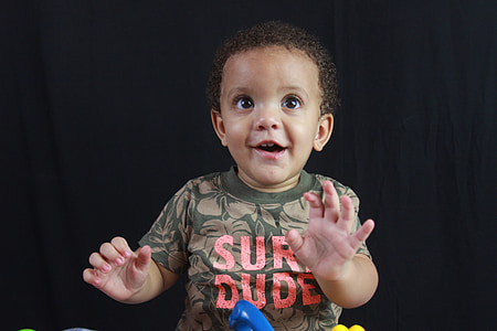 baby standing in front of black fabric covered backdrop