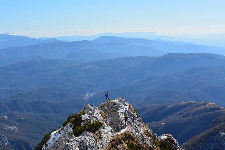 man on top of rock mountain during daytime