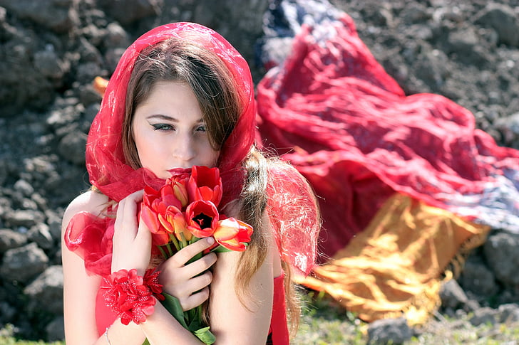 close-up photography of woman wearing red scarf and holding red and yellow tulip flowers