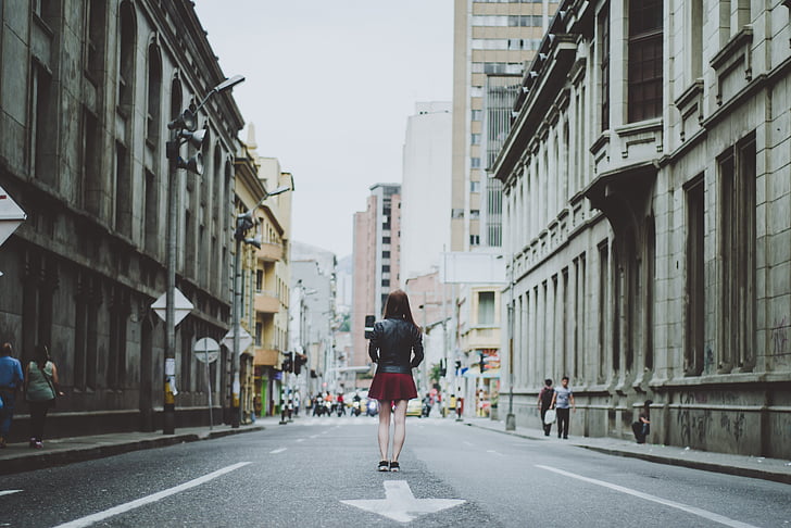 woman wearing red skirt standing in the middle of the city road