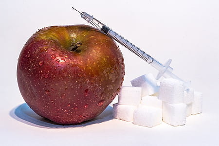 syringe on red apple