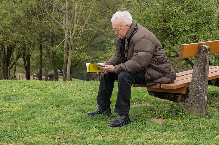 man sitting on the bench reading book