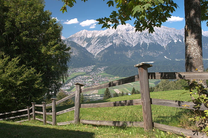 brown wooden fence near trees and mountain near town