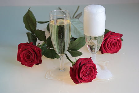 two champagne glasses and three red rose flowers