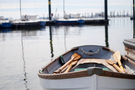 white and brown wooden boat with oars near dock