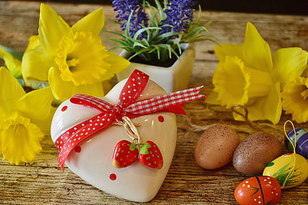white and red ceramic heart lid near two yellow flowers on brown wooden surface