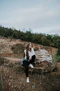 woman sitting on brown stone looking sideway