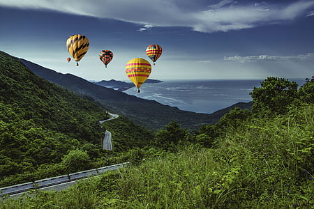 five assorted-color hot air balloon passing through mountains