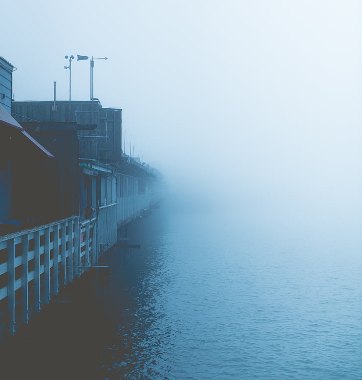 elevated houses beside body of water in foggy weather condition