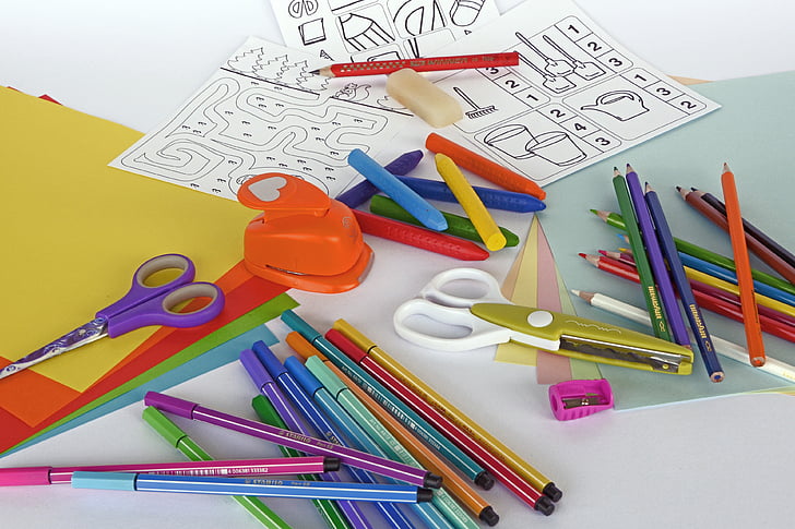 assorted-colored coloring pencils, scissors, sharpeners and papers on panel
