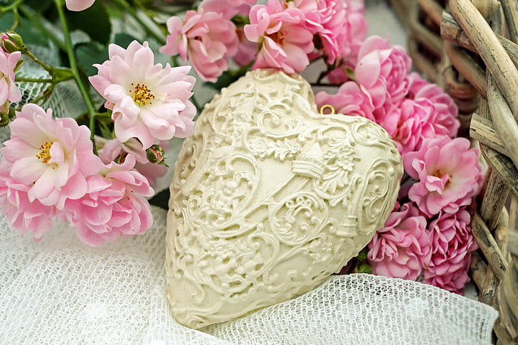 heart-shaped white container on top of white surface and pink petaled flowers