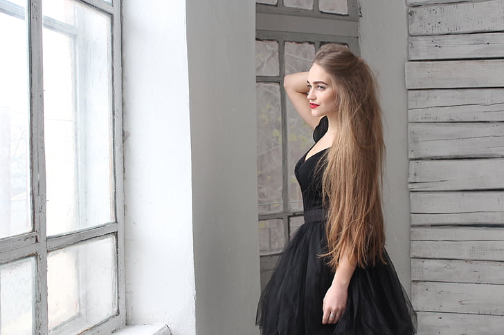 woman wearing black dress standing near window