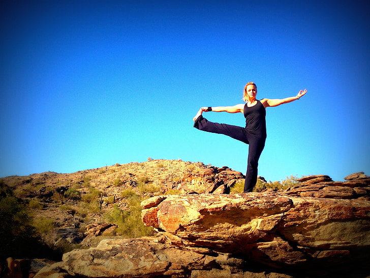 Woman in yoga pose on mountain peak stock photo - OFFSET