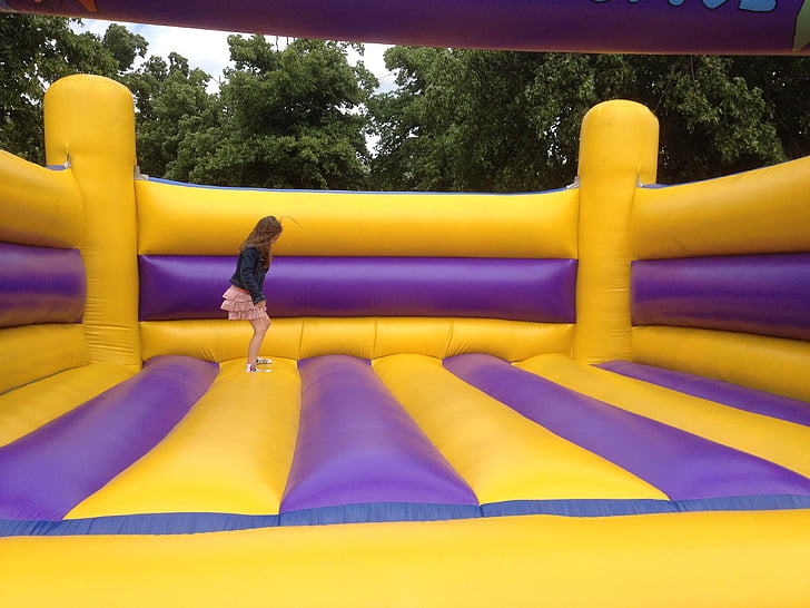girl jumping on yellow and purple inflatable bouncer