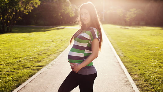 portrait photography of pregnant woman standing in the middle of road