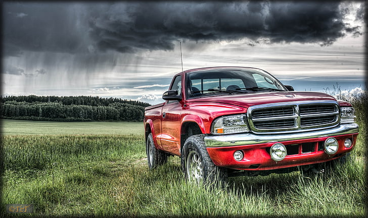 red Dodge truck on grass land under cloudy sky