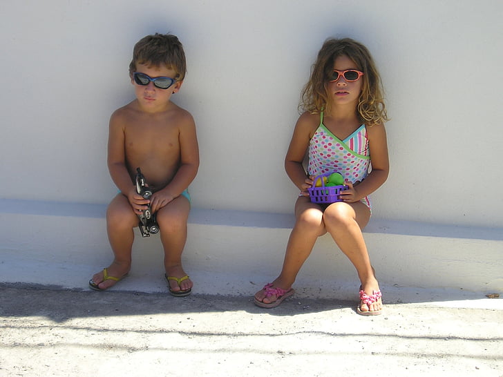 boy and girl sitting on white concrete edge