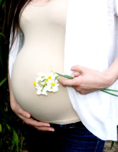pregnant woman holding flowers while holding her belly