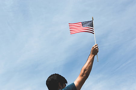 man holding US flag during daytime