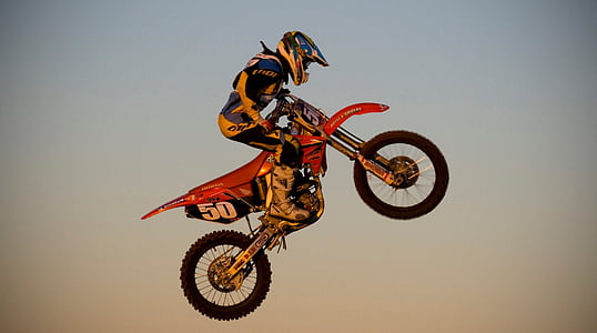 photo of person riding red motocross dirt bike