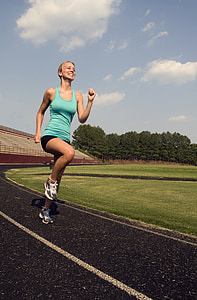 women in blue tank top running on track field during daytime